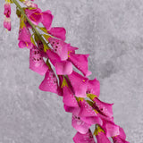 A close up of a fuchsia coloured faux foxglove stem