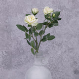 A faux white rose spray shown in a frosted white glass vase