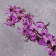 A closes up of a faux lily stem, showing lots of pinkish purple flowers