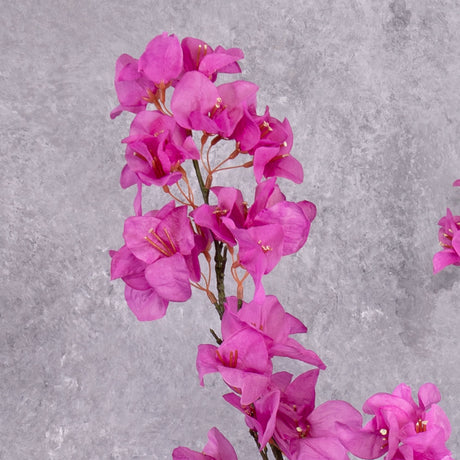 A close up of a faux Bougainvillea spray with bright pink flowers over multiple branchlets