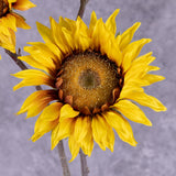 A close up of a single, faux, sunflower head in rich yellow