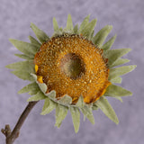 A close up of a single, faux, sunflower head in rich yellow