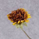 Close up shot of a faux sunflower head with fluffy looking petals in brown and orange