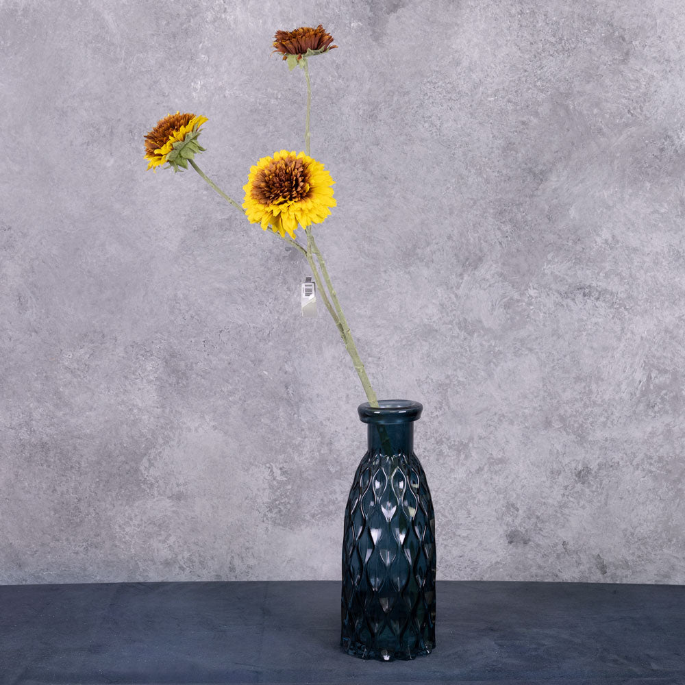 A faux sunflower spray with three separate flowers of different sizes, shown in a blue glass vase