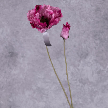 A faux poppy stem with an open flower and a budding flower on two branchlets. The flowers are a dark pink colour with purple tones