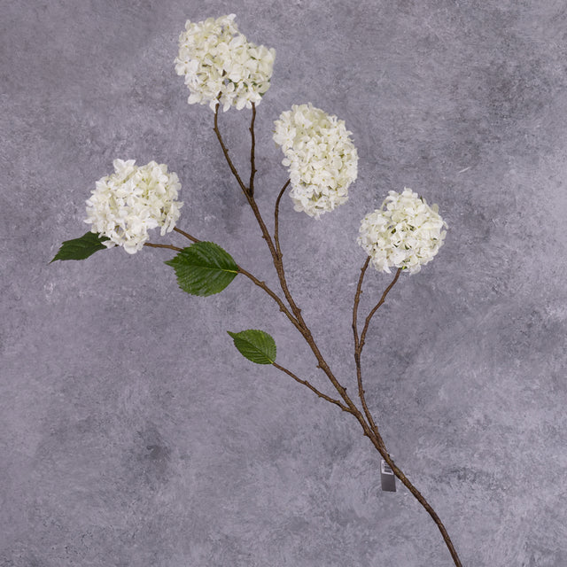 A faux hydrangea spray with four, pom-pom-like cream flowers, and five leaves